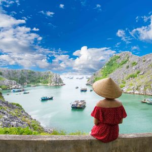 A young traveler girl on the top of mountain in Long Chau island, Cat Ba and enjoy the beauty of seascape. Young girl love wild life, travel, freedom.